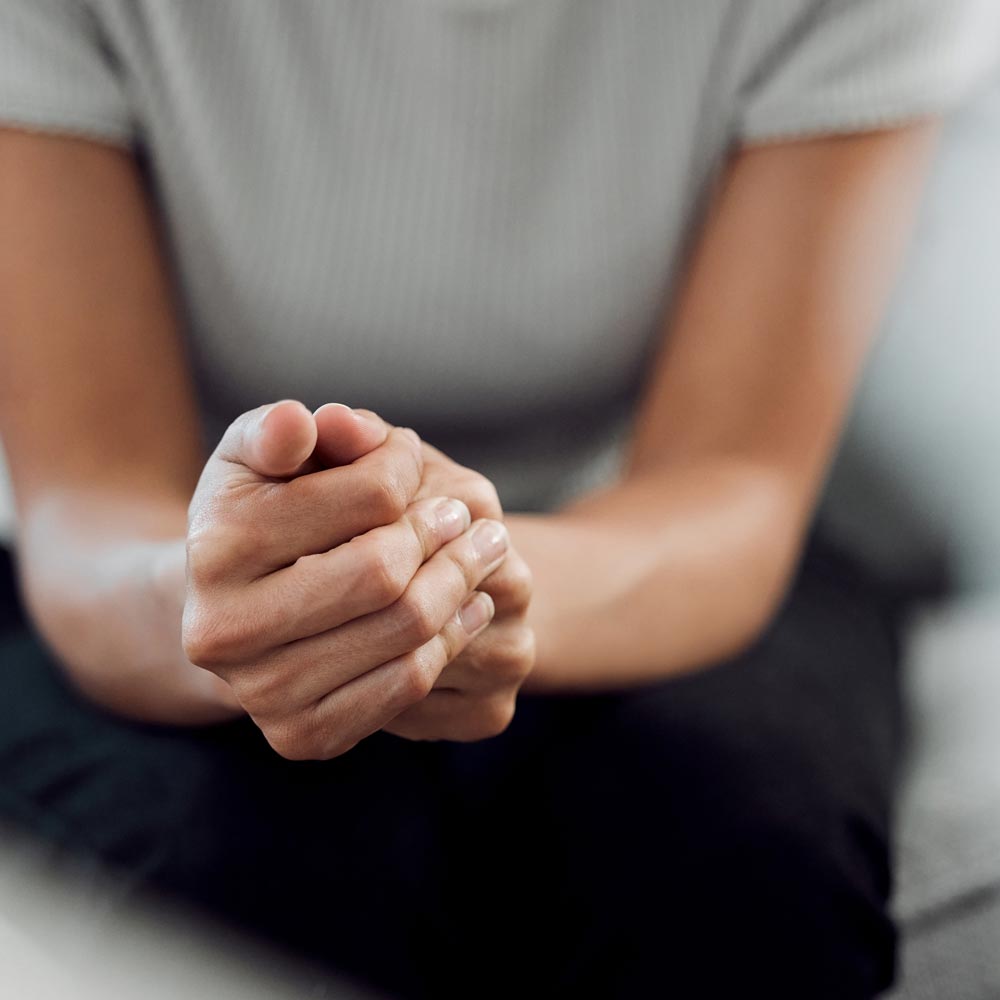 Close-up of a client’s hands clasped during a counselling session.